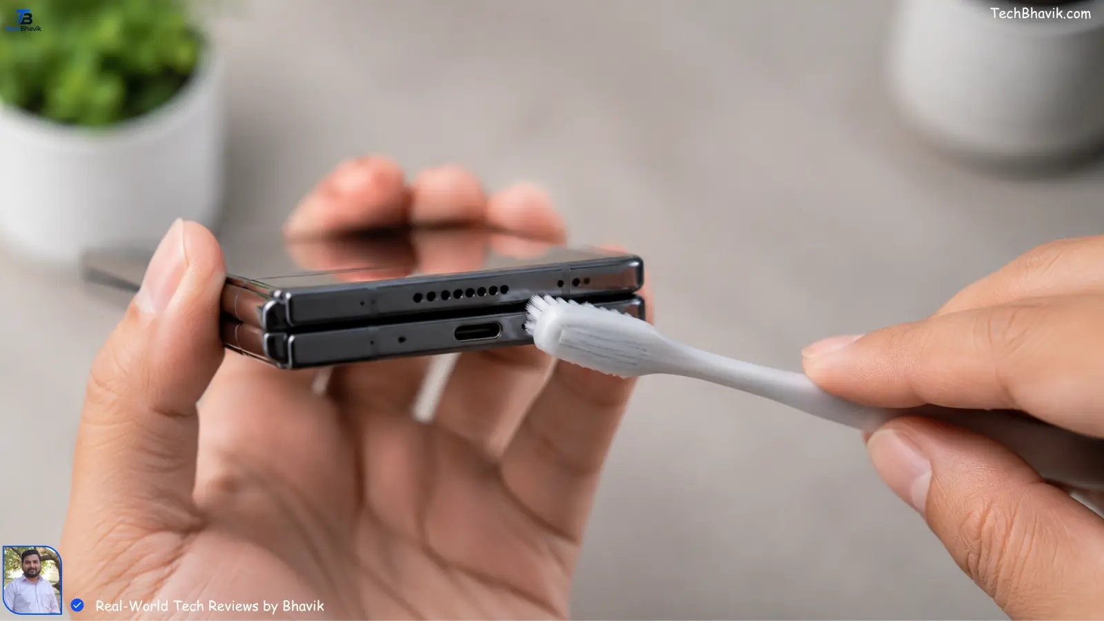 A person using a soft toothbrush to gently clean the charging port and speakers of a foldable phone.Samsung Passport Design